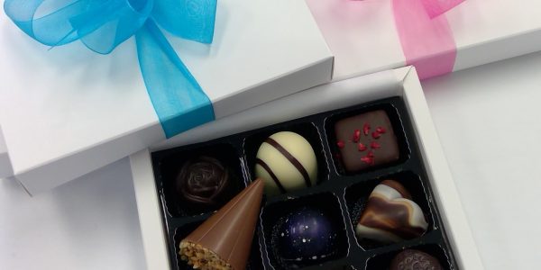 Box of chocolate flavours with blue and pink ribbons on top